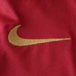 Close-up of a red Barcelona x Coldplay (Special Release) jersey featuring the Nike logo in gold thread.