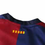Close-up of the collar area of a Barcelona x Coldplay (Special Release) jersey, showing red and blue stripes with yellow detailing.