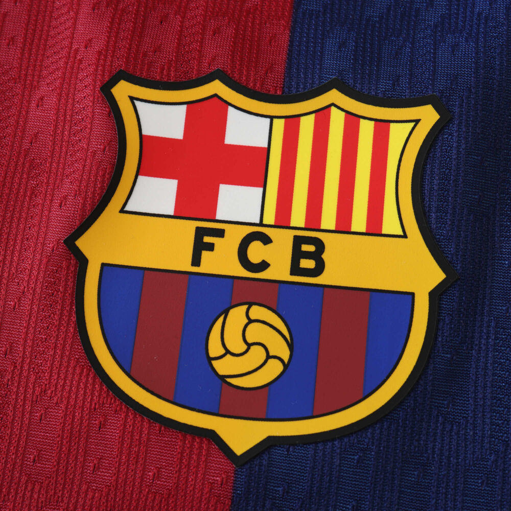 Close-up of the F.C. Barcelona crest on a striped red and blue background for the Barcelona x Coldplay (Special Release) | Player Version.