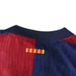 Close-up of Barcelona x Coldplay Player Version jersey, highlighting the red and blue collar with a small yellow-red striped detail.