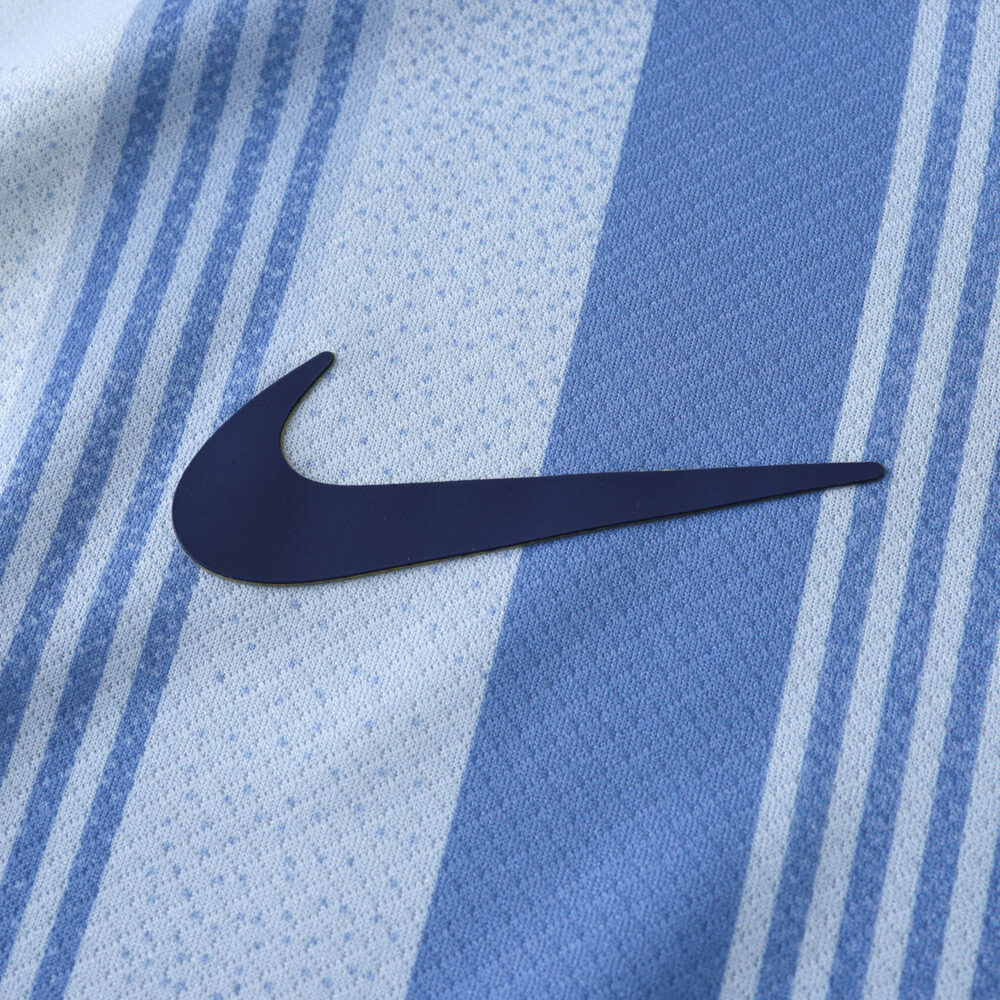 Close-up of the Nike logo on the Tottenham x Travis Scott (Special Release) Fan Version jersey, featuring blue and white stripes.