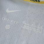 Close-up of the Tottenham x Travis Scott fan version jersey tag showing size M, Dri-Fit fabric, and "Made in Thailand."