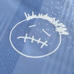Close-up view of a Travis Scott-inspired face emblem on a Tottenham special release fan version jersey.