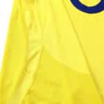 Close-up of the Arsenal Retro Away 2003/04 fan version jersey in yellow with blue detailing, showcasing fabric and stitching.