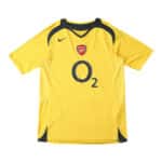 Arsenal Retro Away 2005/06 Fan Version Jersey. Yellow with navy accents, Nike logo, Arsenal crest, and O2 sponsor on the front.