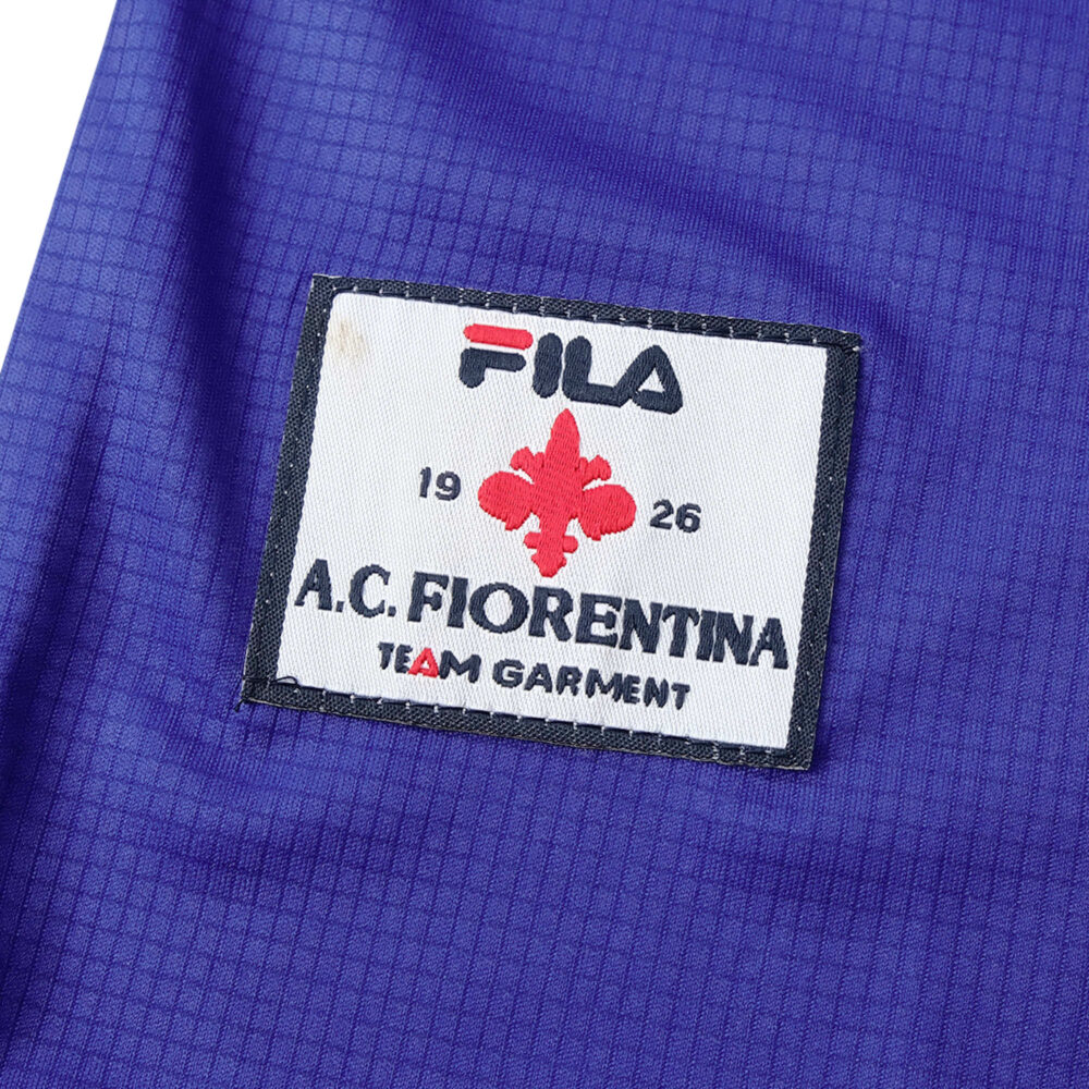 Close-up of the Fiorentina Retro Home 1998/99 jersey featuring the Fila logo and A.C. Fiorentina crest with "Team Garment" text.