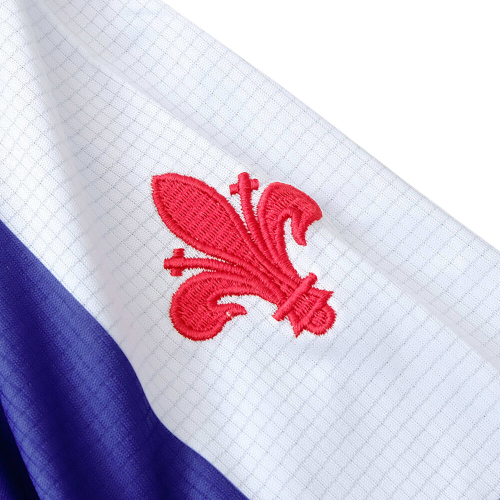 Close-up of the Fiorentina Retro Home 1998/99 Fan Version jersey, featuring a red lily emblem on a white and purple background.