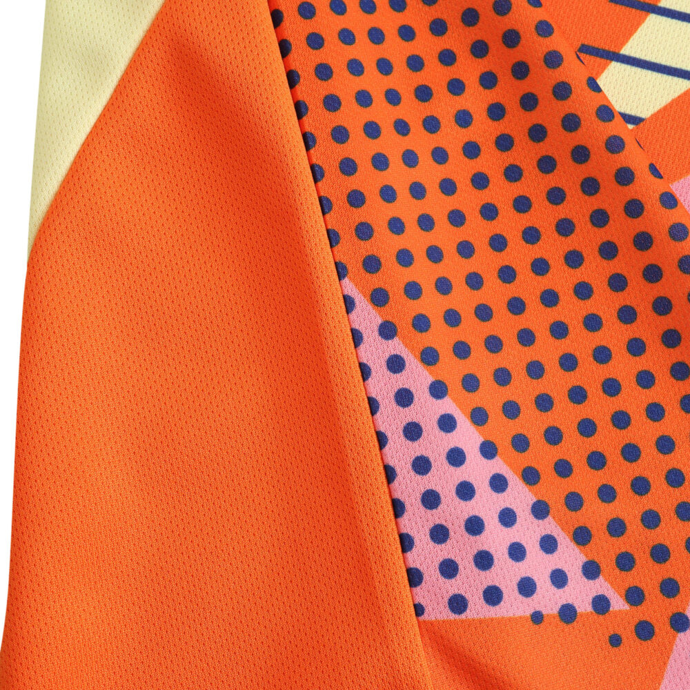 Close-up view of Italy Goalkeeper 2024 Fan Version jersey fabric, featuring orange color with purple and dark blue polka dots.