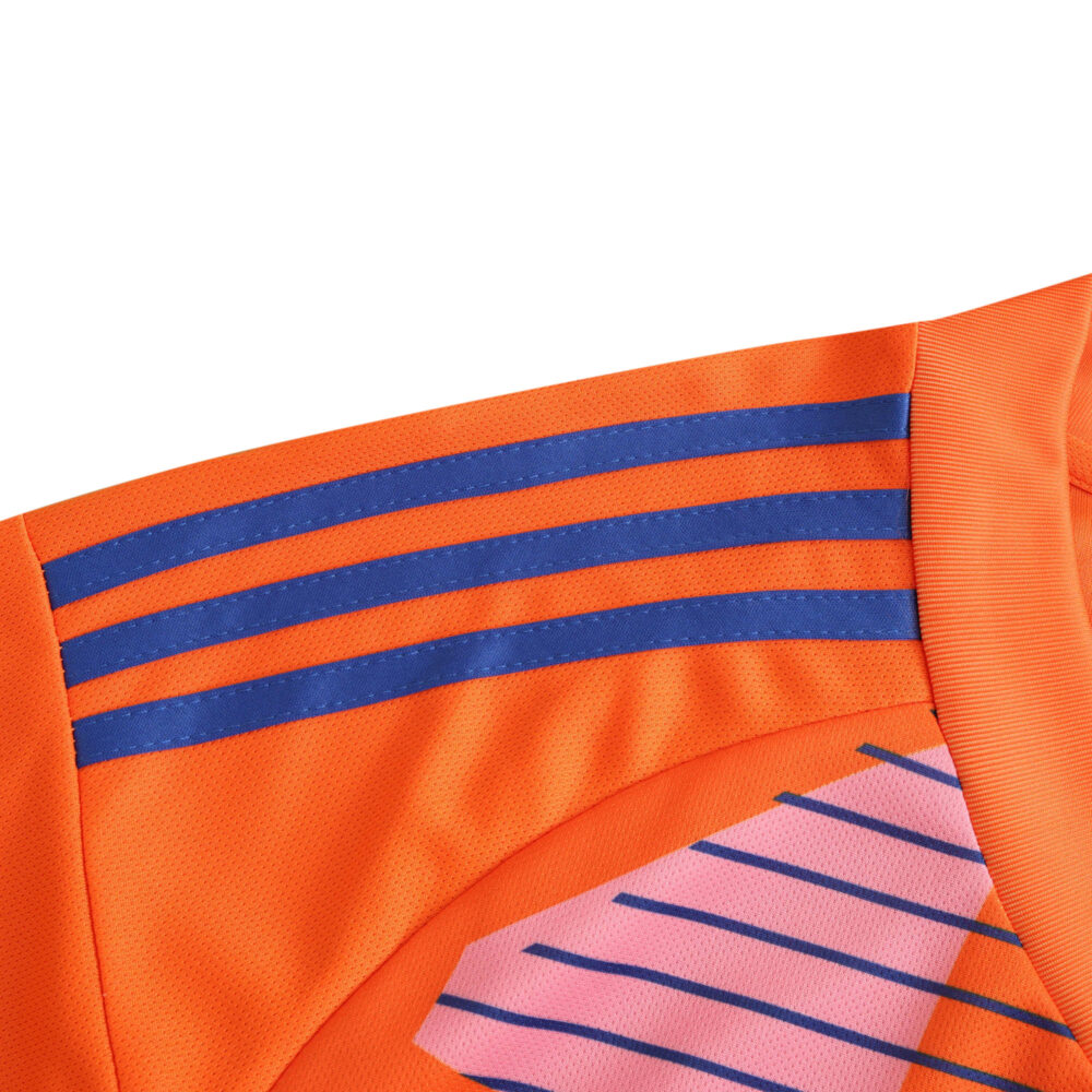 Close-up of Italy Goalkeeper Fan Version jersey for 2024, featuring orange fabric with blue and pink stripe patterns.