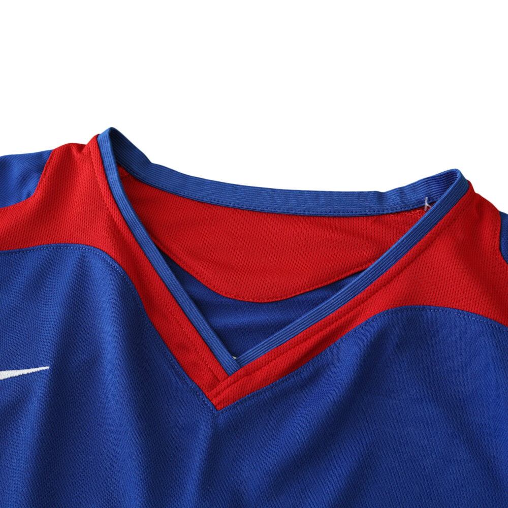 Close-up of the Manchester United Retro Away 2005/06 Fan Version jersey, featuring blue fabric with red trim around the V-neck.