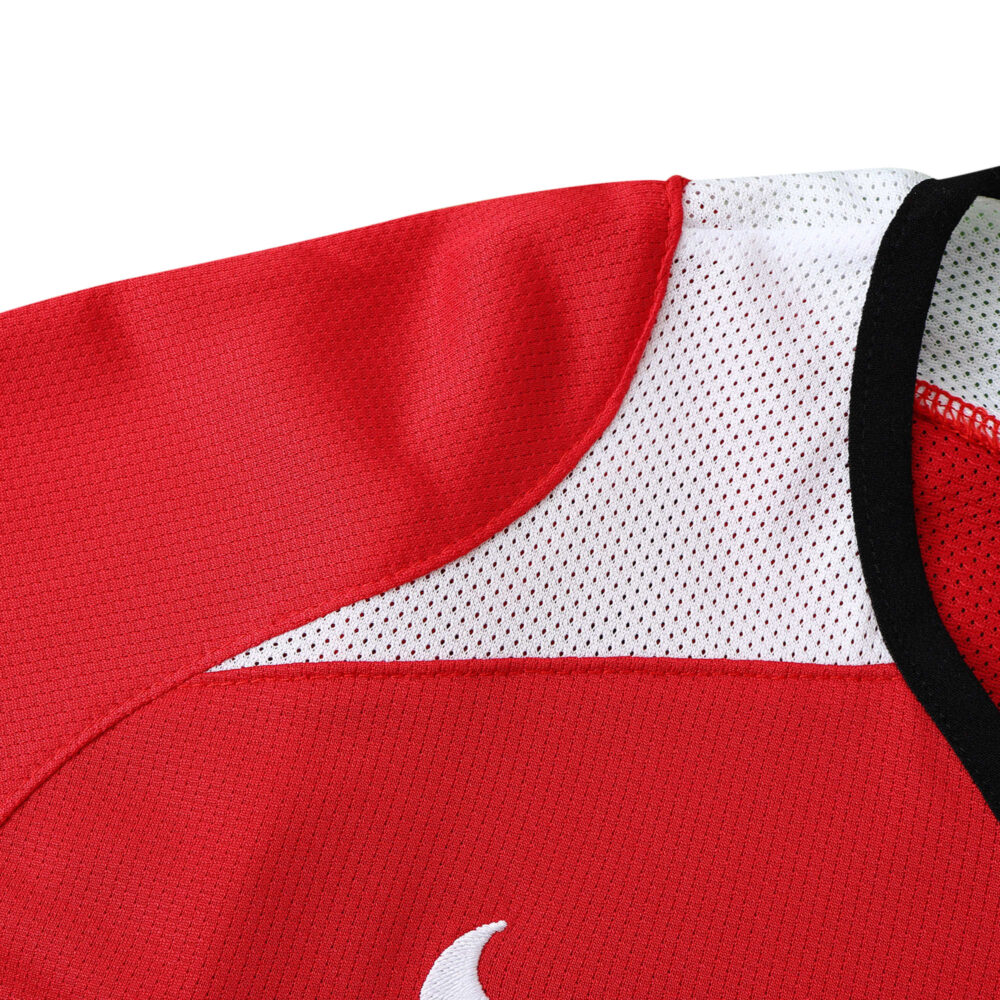 Close-up of the Manchester United Retro Home 2004/05 Fan Version jersey, showing red fabric and white mesh shoulder detail.