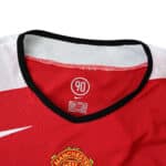 Close-up of Manchester United Retro Home 2004/05 Fan Version jersey collar with Nike logo and club badge in view.