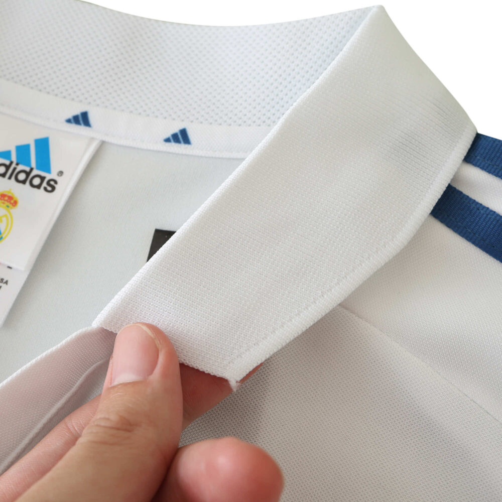 Close-up of the collar and Adidas tag on the Real Madrid Retro Home 2001/02 Fan Version jersey, highlighting fabric detail.