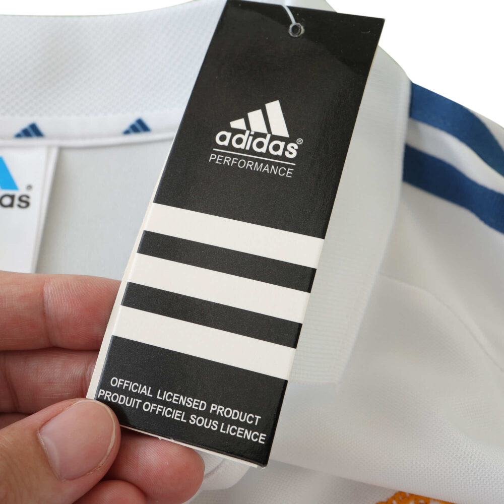 Real Madrid Retro Home 2001/02 Fan Version jersey with Adidas performance tag held by hand, showcasing the official licensed product.