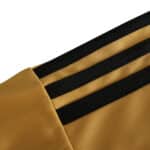 Close-up of the shoulder area of the Spain Retro Away 2008 Fan Version jersey, showing gold fabric with three black stripes.