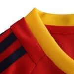 Close-up of Spain Retro Home 2002 soccer jersey Fan Version, showing red fabric with black stripes and a yellow collar.