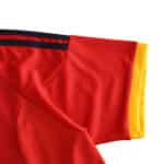 Close-up of the Spain Retro Home 2002 soccer jersey sleeve, featuring red fabric with yellow and black accents.