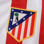 Atlético Madrid 2025/26 Home Fan Version jersey crest on red and white striped fabric.