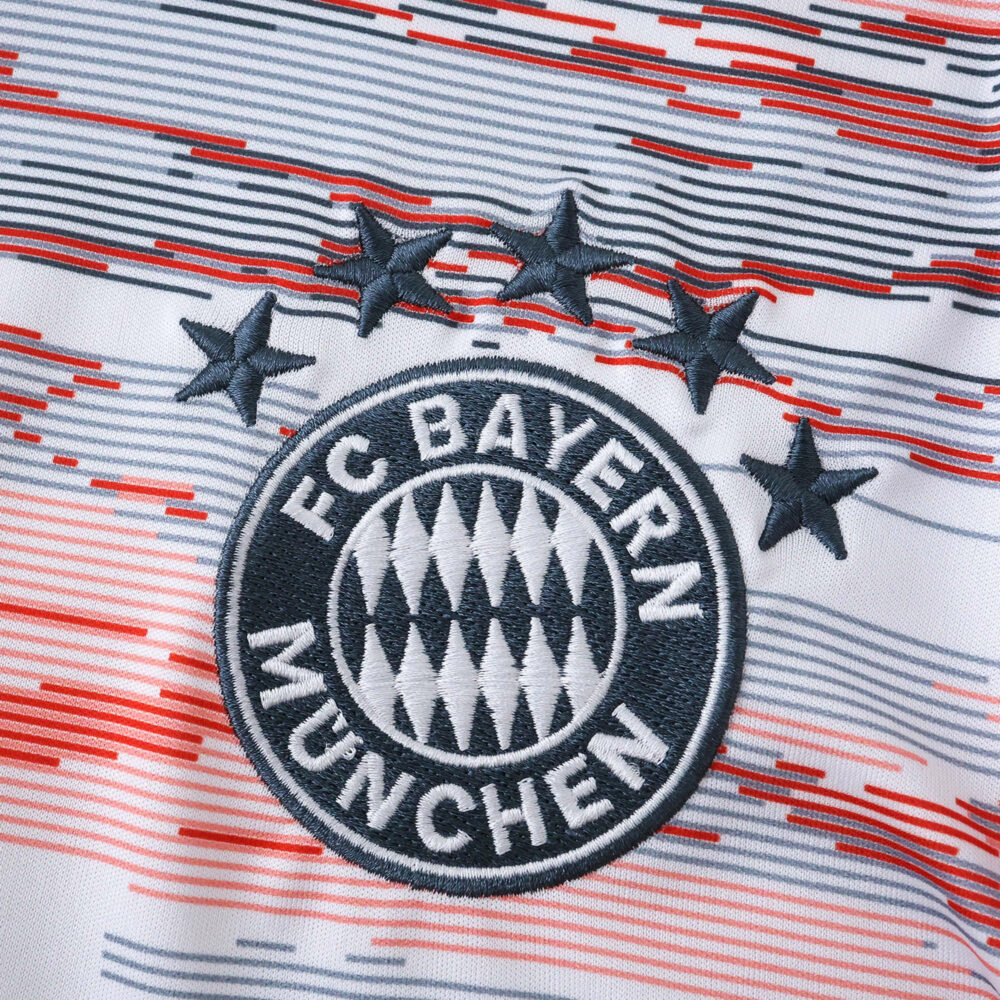 Close-up of FC Bayern Munich crest with four stars on the 2025/26 away fan jersey, featuring red and gray stripes.