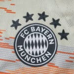 Close-up of FC Bayern Munich crest with five stars on the 2025/26 away player jersey.