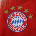 Close-up of FC Bayern Munich crest with five stars on the 2025/26 home player version jersey.