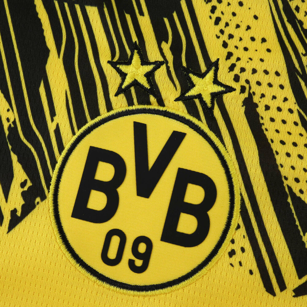 Close-up of the Borussia Dortmund 2025/26 home jersey crest with two stars and bold graphic details.