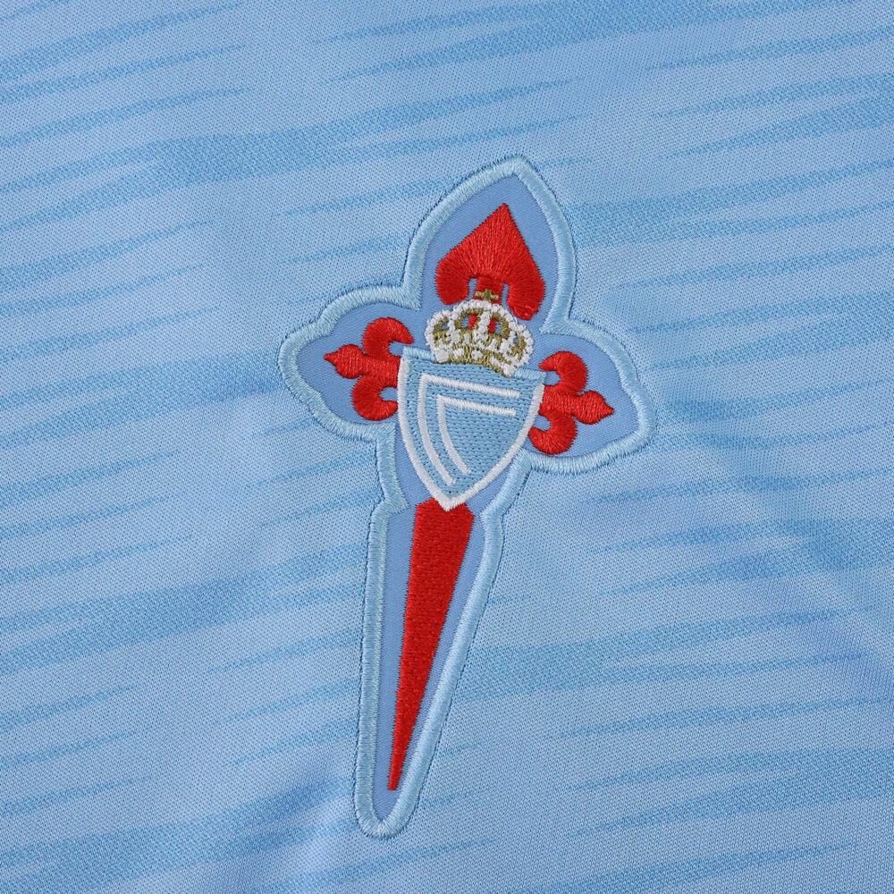 Close-up of the Celta Vigo crest on the 2025/26 home fan version jersey in light blue fabric.
