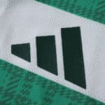 Close-up of the Adidas logo on the Celtic Home 2025/26 Player Version jersey in green and white.