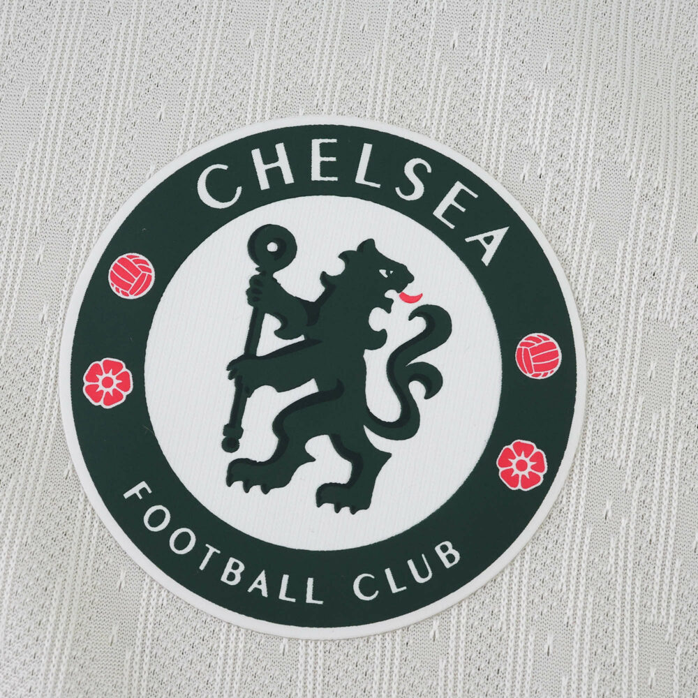 Chelsea FC badge on the 2025/26 away player jersey, displayed against a textured white fabric background.