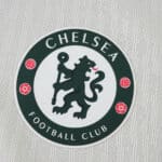 Chelsea FC badge on the 2025/26 away player jersey, displayed against a textured white fabric background.