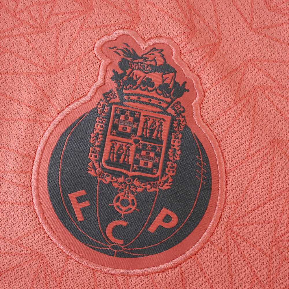 Close-up of the FC Porto crest on the 2025/26 Away Fan Version jersey in red and black.
