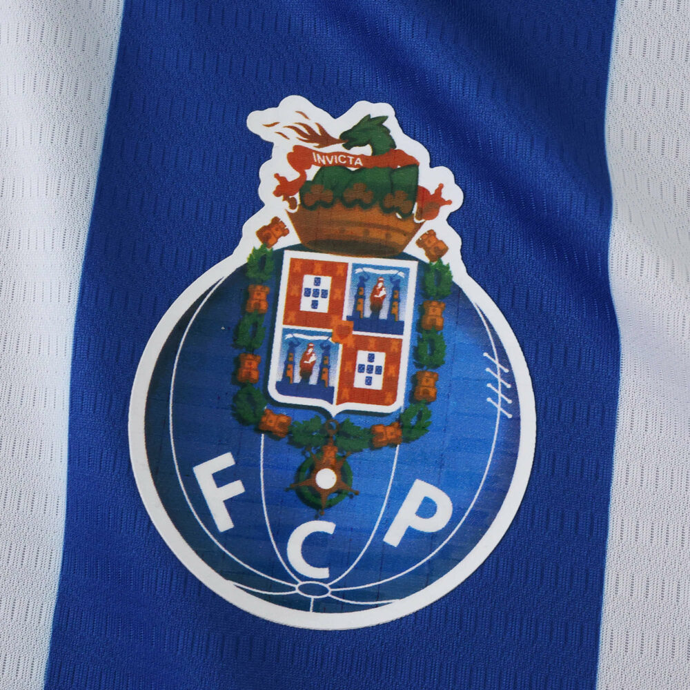FC Porto crest on blue and white striped fabric, featured on the 2025/26 home fan version jersey.