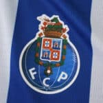 FC Porto crest on blue and white striped fabric, featured on the 2025/26 home fan version jersey.