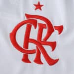 Red Flamengo crest with star embroidered on white fabric, featured on the 2025/26 Away Fan Version jersey.