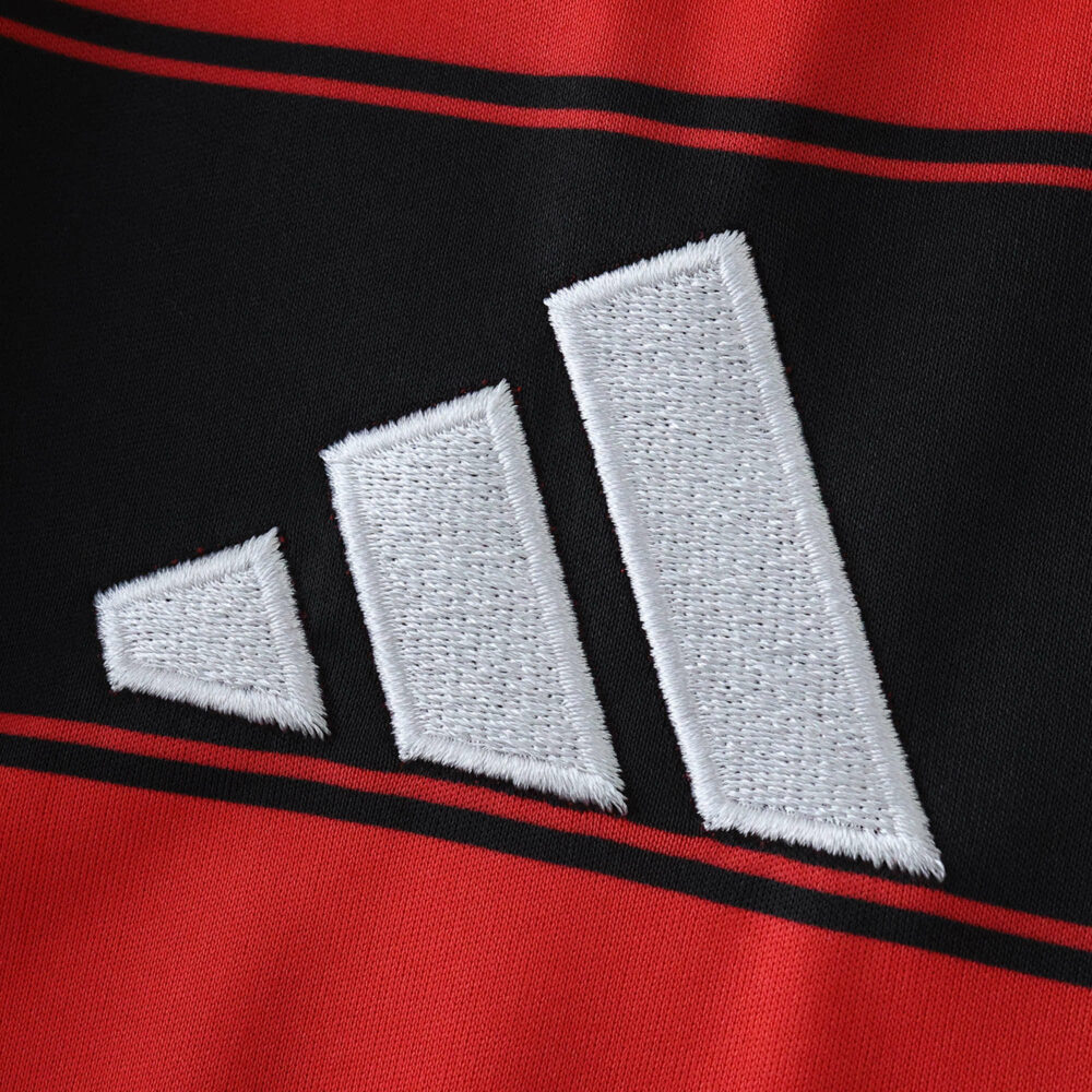 Close-up of the Adidas logo embroidered on the red and black Flamengo 2025/26 home fan jersey.