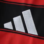 Close-up of the Adidas logo embroidered on the red and black Flamengo 2025/26 home fan jersey.
