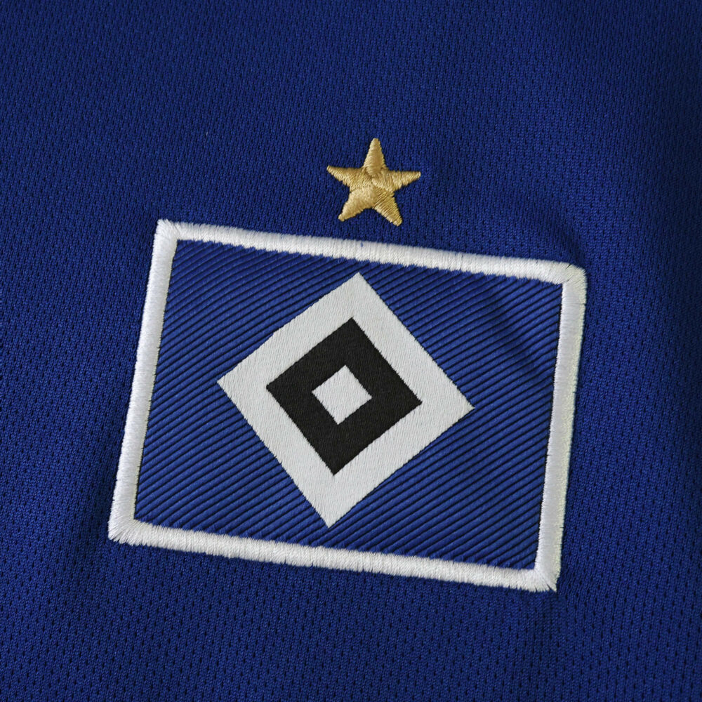 Close-up of Hamburger SV logo with a gold star on the 2025/26 away fan version jersey fabric.
