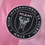 Close-up of Inter Miami CF 2025/26 home jersey badge on pink fabric, featuring club crest and text.
