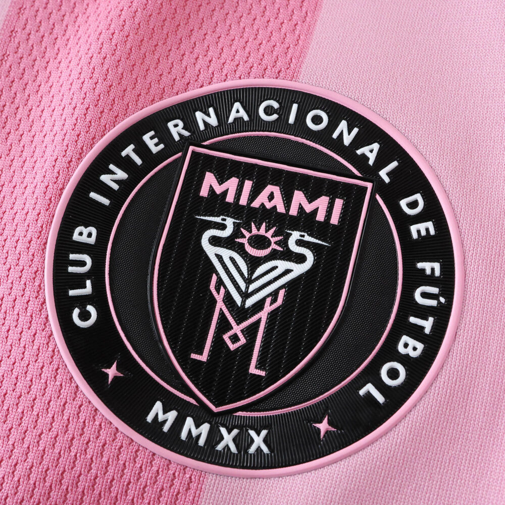 Close-up of the Inter Miami CF home 2025/26 player version jersey badge on pink fabric.