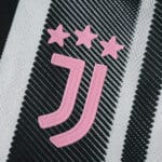 Close-up of the pink Juventus logo with three stars on the 2025/26 home player version jersey.