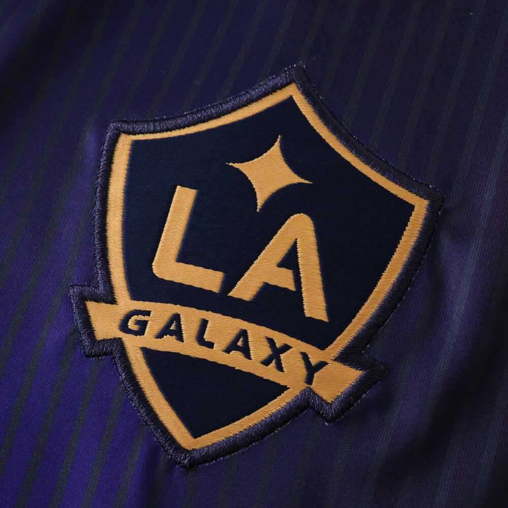 Close-up of the LA Galaxy crest on the 2025/26 away fan version jersey with navy and gold details.