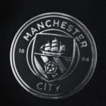 Manchester City crest on the 2025/26 Away Player Version jersey, featuring ship and rose emblems.