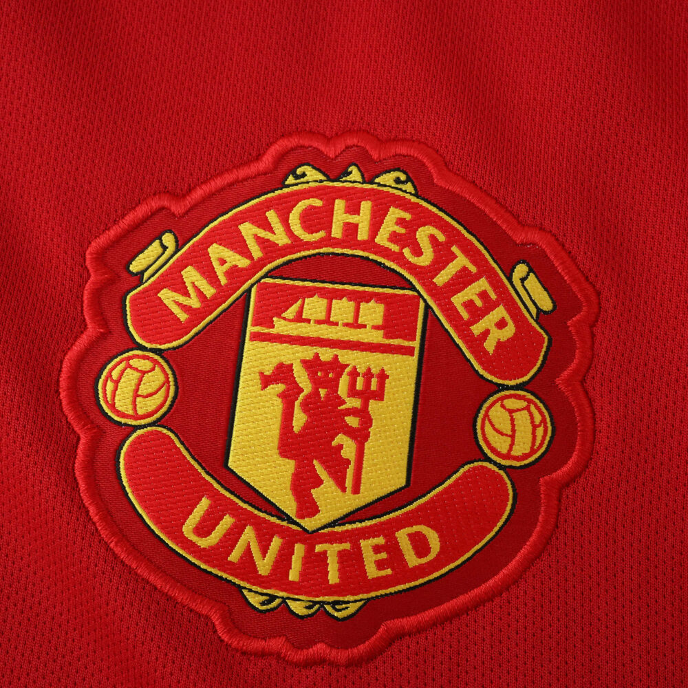 Manchester United crest embroidered on the red 2025/26 home fan version jersey fabric.