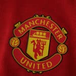 Manchester United crest on the red 2025/26 Home Player Version jersey fabric.