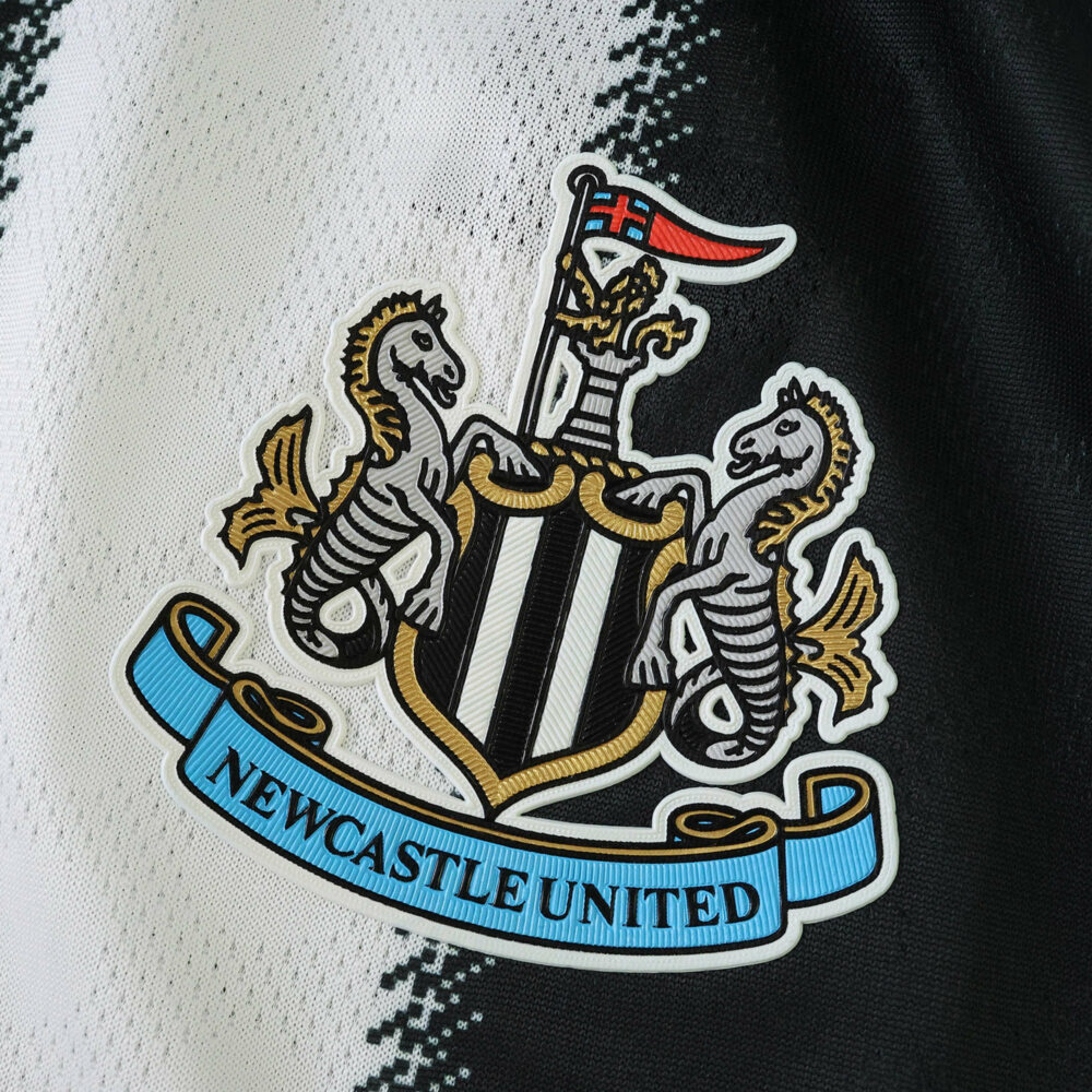 Newcastle United 2025/26 home jersey badge, close-up of the club crest on black and white fabric.
