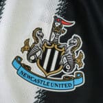 Newcastle United 2025/26 home jersey badge, close-up of the club crest on black and white fabric.