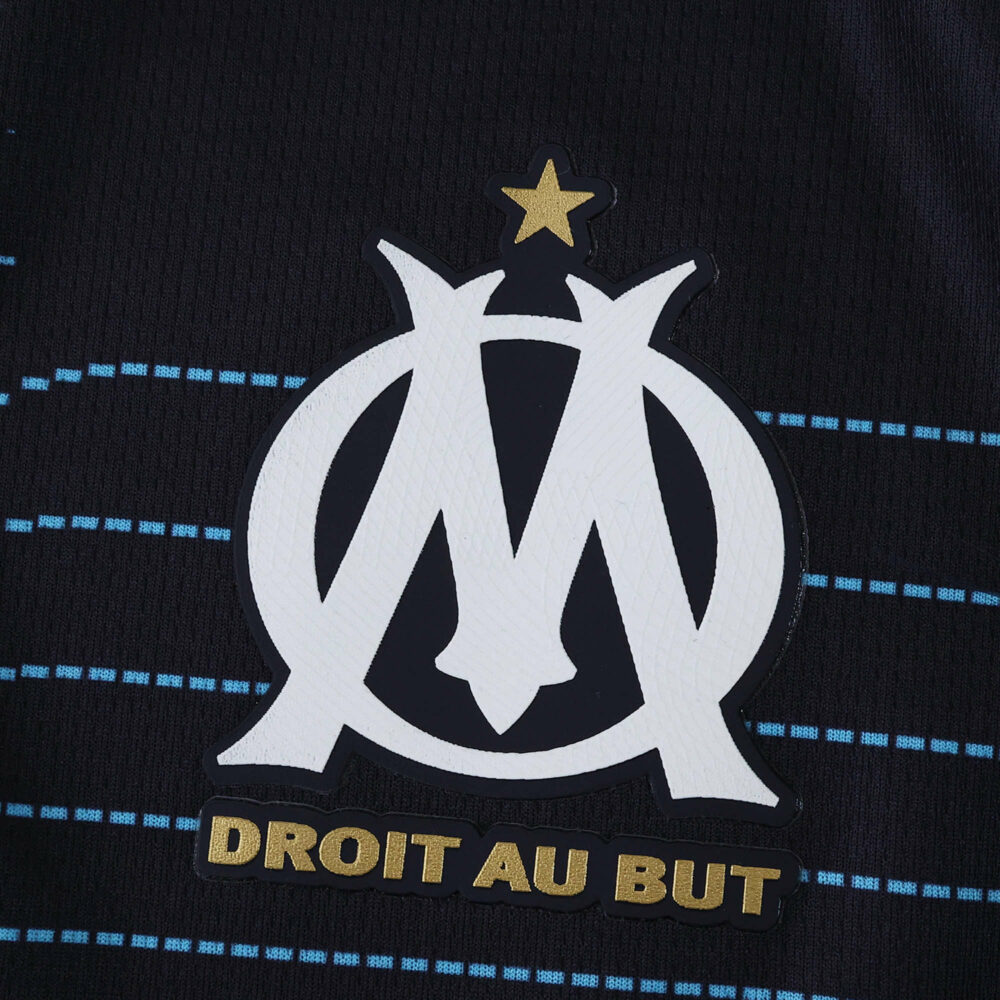 Olympique Marseille away jersey 2025/26 fan version crest with gold star and "Droit Au But" text.