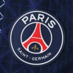 Close-up of the Paris Saint-Germain 2025/26 home jersey badge, featuring the club logo on dark blue fabric.