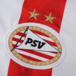 Close-up of the PSV Eindhoven 2025/26 Home Fan Version jersey badge with two gold stars above the crest.