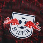 RB Leipzig logo on the 2025/26 third fan version jersey with a red and black patterned background.